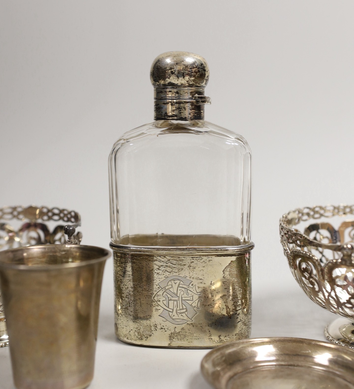 A pair of Edwardian pierced silver bonbon baskets, Nathan & Hayes, Birmingham, 1909, diameter 10.1cm, a pair of silver bonbon dishes, an Edwardian silver mounted glass hip flask, by Charles & George Asprey, London, 1908
